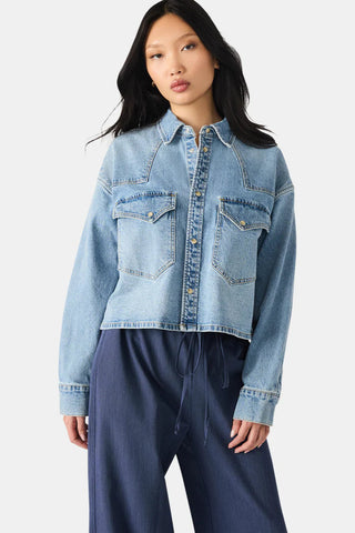 Woman wearing a light blue denim jacket on a white background